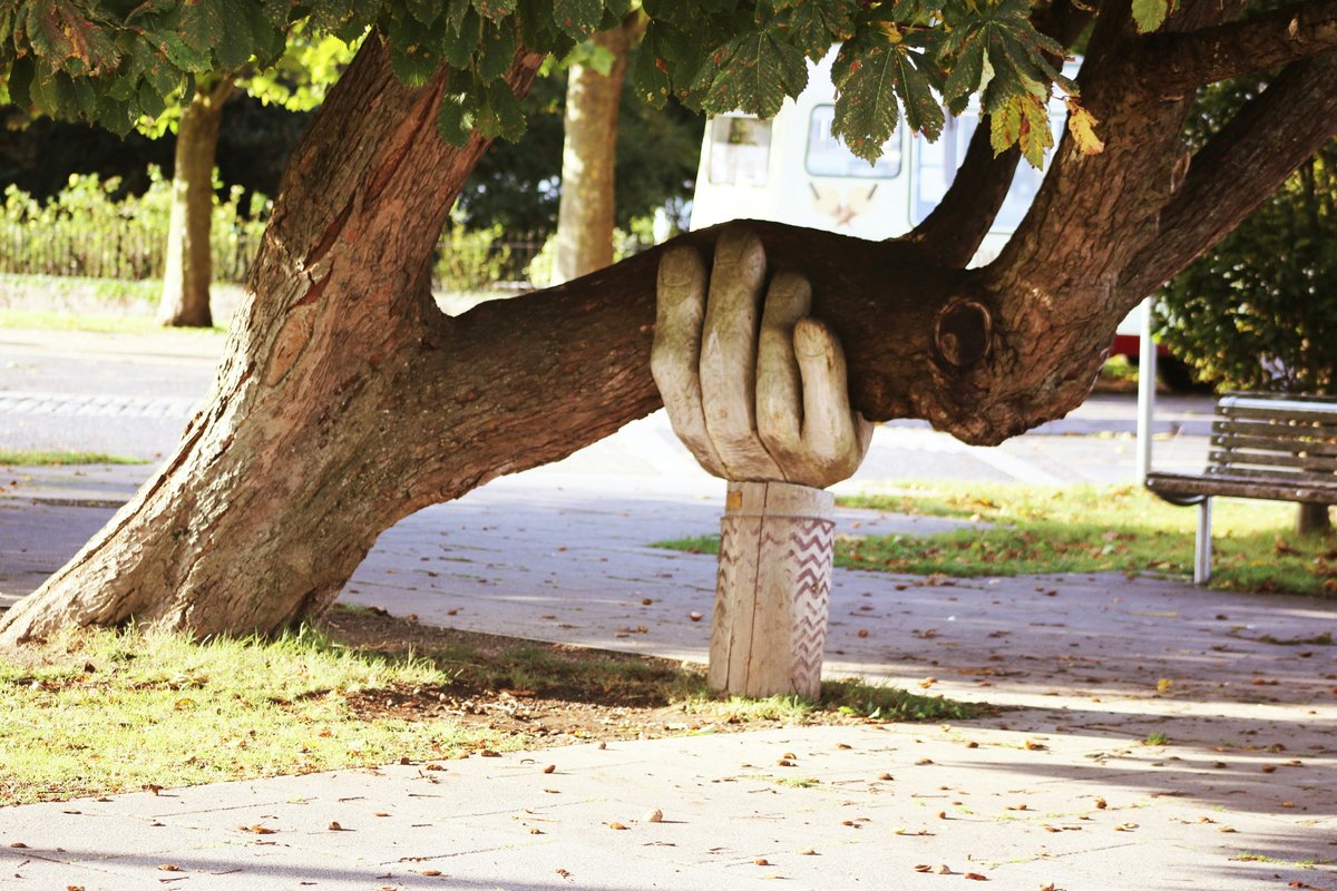 A sculpted hand supporting a tree branch